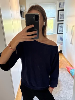 Mörkblå off shoulder sweatshirt - Mysig mörkblå sweatshirt med avslappnad passform och off shoulder-design. Tröjan har trekvartsärmar och bred mudd i nederkant. 