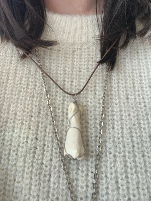 Halsband med benhänge och kedja - Unikt halsband med ett benformat hänge insvept i metalltråd. Hänget sitter på en silverfärgad kedja och ett brunt läderband. Perfekt för dig som gillar statement-smycken och vill sticka ut med något annorlunda.