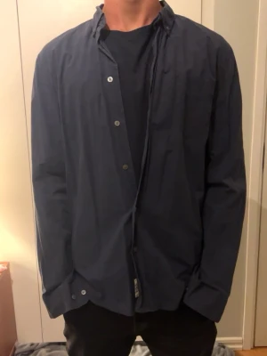 Mörkblå skjorta från acne studio / Modellen är 182 - Säljer en stilren mörkblå skjorta med klassisk krage och knäppning framtill. Skjortan har långa ärmar och en relaxed passform, perfekt att bära över en t-shirt. Materialet känns lätt och bekvämt. Rensar min garderob därför ja säljer denna pärla. Nypris: 3500 || Mitt pris: 900