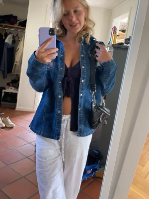 Blå jeansjacka  - Snygg blå jeansjacka i klassisk modell med silverfärgade knappar och coola nitar på ena bröstfickan. Jackan har en rak passform och är gjord i denim. 