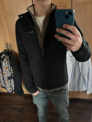 Mörkblå mockaliknande vårjacka - Snygg mörkblå jacka i mockaimitation med minimalistisk design. Jackan har ståkrage och diskreta sömmar. Passar perfekt till jeans för en clean och stilren look. Perfekt till våren!