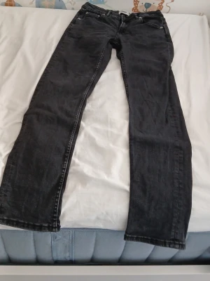 Svarta jeans med rak passform - Säljer ett par svarta jeans med klassisk rak passform och fem fickor. Jeansen har knapp- och dragkedjegylf samt diskreta sömmar. Perfekta till en avslappnad stil och funkar året runt.