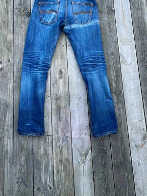 Nudie Jeans - Säljer ett par selvage Nudie Jeans med slitningar och whiskers på knäna och baksidan. Jeansen är lite slimmade men ändå åt det raka hållet. Storlek 30-34 men lite mer som 32 beroende på tvättningar. Det är dry selvage med en orange söm profil. Tveka inte om du har några frågor. Pris kan minska vid väldigt snabb affär.