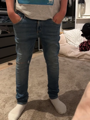 Blå slim fit jeans med slitning - Blåa jeans med en slitning