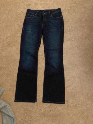 Mörkblå bootcut jeans låd midja - Snygga mörkblå bootcut jeans. Jeansen har en lätt tvättad look och raka ben som går ut lite nedtill. 