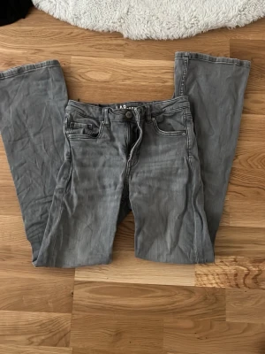 Gråa bootcut jeans från Kappahl - Säljer ett par gråa bootcut jeans från LAB Industries. Jeansen har klassisk femficksdesign, normalhög midja och vida ben. Tillverkade i denim med snygg tvättad look och detaljerade sömmar. Perfekta för dig som gillar en avslappnad men trendig stil. Nästan aldrig använt.