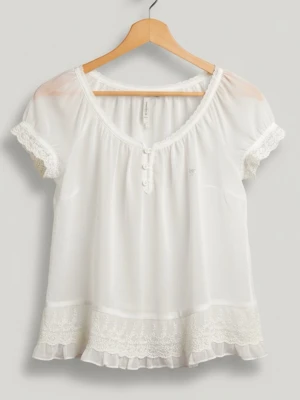 Topp från abercrombie and fitch - Söt och luftig vit blus med korta ärmar, spetsdetaljer vid ärmslut och nederkant samt volang längst ner. Blusen har rund halsringning med knappar framtill och broderade blommor vid fållen. Från abercrombie and fitch storlek s