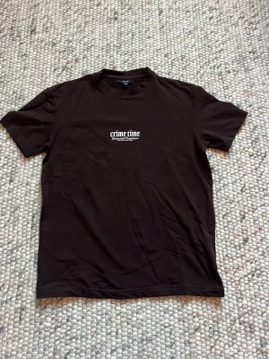 Svart t-shirt Crime Time tryck - Cool svart t-shirt från New Yorker med texten 'crime time' tryckt på bröstet och stort grafiskt tryck med drakar och olika texter på ryggen. Klassisk passform och rund hals. Perfekt för dig som gillar streetwear och statement-plagg.
