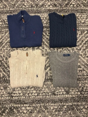 Stickade tröjor från Polo Ralph Lauren - Fyra stickade tröjor från Polo Ralph Lauren i färgerna marinblå, mörkblå, beige och grå. Två har halv dragkedja och två är klassiska kabelstickade modeller. Alla har den ikoniska broderade loggan på bröstet. Tröjorna är i storlekarna S och M. Hör av er vid eventuella frågor eller funderingar!!