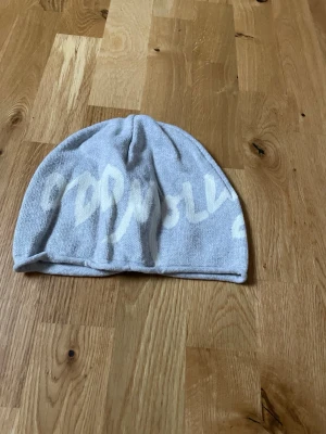 Ljusgrå mössa från Odd Molly - Säljer en ljusgrå mössa från Odd Molly med vit textdetalj. Mössan är mjuk och har en enkel, klassisk form som passar perfekt till kalla dagar. Materialet är stickat och ger en avslappnad och trendig look.