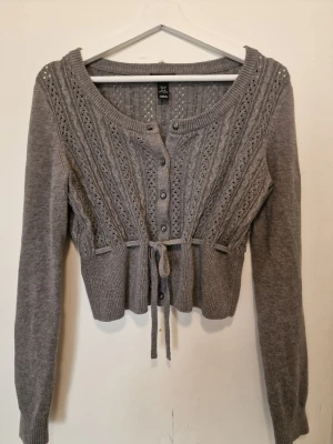 Grå kofta med knytband - Grå stickad kofta med knytning som ger en söt vintagekänsla. Lite Blair Waldorf/Diaries of vampire, y2k vibes 🩶 passar även mig som har S. 