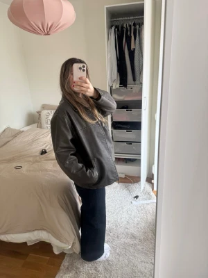 Oversized brun skinnjacka - Säljer en oversized brun skinnjacka med raka ärmar och enkel design. Jackan har en avslappnad passform och dragkedja framtill. Perfekt för dig som gillar en cool och tidlös look. Märke saknas.