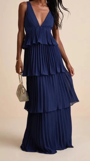 Marinblå långklänning med volanger - Elegant marinblå långklänning med djup v-ringning och flera lager av plisserade volanger. Klänningen är ärmlös och har en flytande, luftig passform som ger en sofistikerad look. Perfekt till balen🥰 skriv för prisförslag eller fler bilder