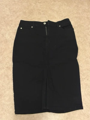 Svart pennkjol med fickor - Säljer en svart långkjol i pennmodell med klassisk femficksdesign och dragkedja framtill. Kjolen har bälteshällor och bakfickor, perfekt för en clean och stilren look. Materialet känns som bomull med lite stretch.