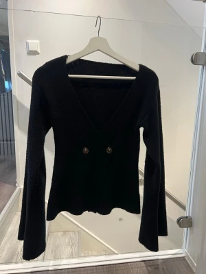 Svart kofta från Shein, S - Snygg svart kofta med djup v-ringning och två  knappar framtill. Koftan har långa, lätt utsvängda ärmar och är gjord i ett mjukt stickat material. Passar mig som brukar ha XS/S i toppar💖