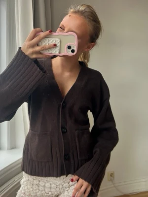 Mörkbrun stickad kofta med fickor💖💖✨ - Mysig mörkbrun stickad kofta med v-ringning och stora knappar framtill. Koftan har två framfickor och breda ribbade muddar vid ärmslut och nederkant. Perfekt för lager på lager och en avslappnad look.