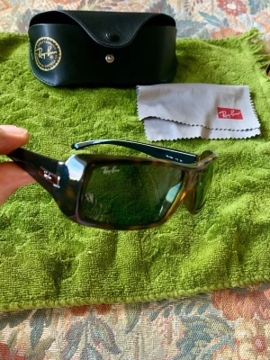 Ray-Ban solglasögon - Snygga solglasögon från Ray-Ban med rektangulära bågar i mörkbrunt plastmaterial och tonade glas. medföljande svart fodral och putsduk.