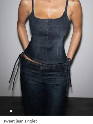 Mörk denim korsettlinne - Trendig mörkblå korsettopp i denim med smala axelband och figurnära passform. Toppen är oanvänd med lappen kvar och slutsåld på ginas hemsida. 