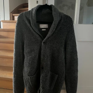 Mörkgrå stickad kofta - Cardigan/kofta från These Glory Days i ull. Mycket bra skick
