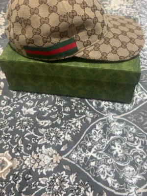Gucci beige GG keps med röd-grön detalj - Säljer en beige keps från Gucci, Den är i mycket bra  skick 8,2/10, självklart äkta, pris ej hugget i sten. Vid frågor är det bara och skriva.