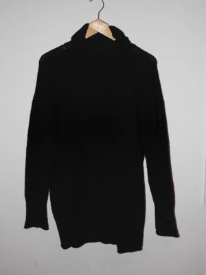 Svart polotröja stickad - En svart stickad polotröja/klänning med lång ärm och hög krage. Tröjan har en enkel och stilren design, perfekt för lager på lager och passar till det mesta, går att bära både som tröja och klänning. Materialet är mjukt och bekvämt