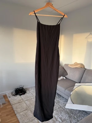 Svart långklänning från Skims - Svart långklänning från Skims med smala justerbara axelband. Formar kroppen snyggt!