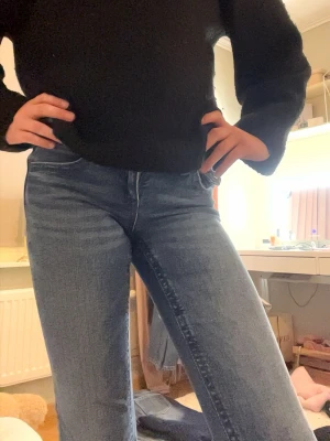 Blå  jeans med brodyr - Säljer ett par blå jeans från ginatricot med ikonisk broderad ficka bak och silverfärgad knapp. Jeansen har en klassisk utsvängd form och är tillverkade i denim med lätt tvättad look. Perfekta för dig som vill ha en cool och tidlös stil.