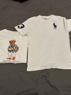 Ralph Lauren T-shirts - Två stycken vita Ralph Lauren T-shirts. En med björn och en med den klassiska hästen och en ”3a” på ärmen. Båda är storlek:L i barnstorlek (14/16). 125kr styck eller 200 för bpfa