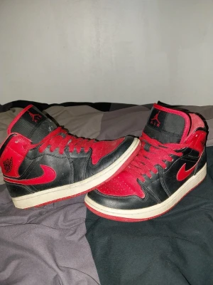 Nike Air Jordan 1 Retro svart röd - Säljer ett par Nike Air Jordan 1 Retro sneakers i svart och rött läder med klassisk röd swoosh och röda skosnören. Storlek 40.5 passae ju självklart 40 och 41 använda i använt skick.