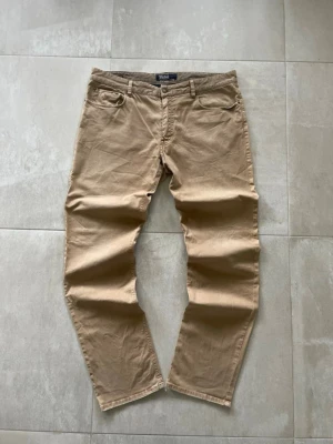 Beige chinos från Polo Ralph Lauren - Snygga beige chinos från Polo Ralph Lauren med klassisk passform och broderad logga ovanför fickan. Tillverkade i mjukt bomullstyg och har fem fickor samt bälteshällor. Perfekta för en clean och stilren look. Mått 📏 Totallängd: 110cm Midjelängd: 48cm Byxlängd: 85cm Lårviddlängd:  31cm Skador 🔧: Lite skador vid baksidan av båda benen  Storlek 🧍: W38/L34 (56/L)  Passform: Slim  Jag kan förhandla mig till lägre pris.🙋💵 Om du har några frågor, vänligen skriv till mig 🤗