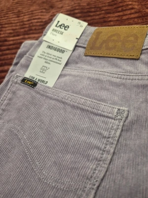 Helt nya! Vintage Lee Breese Flare high-waist corduroy lila byxor, storlek 29 33 - Ljuslila manchesterbyxor från Lee med flared ben och klassisk femficksdesign. Byxorna har en snygg Lee-logga på bakfickan och är tillverkade i mjukt manchestertyg. Perfekt för dig som vill ha en cool och trendig look.