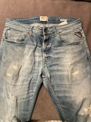 Ljusblå slitna jeans från Replay - Säljer ett par ljusblå jeans från Replay med snygga slitningar och tvättad look. Klassisk femficksmodell med Replay-logga på fickan. Jeansen är slim fit och är perfekta för en trendig stil. Pris kan diskuteras. Kan även tänka mig att byta mot något snyggt plagg:).