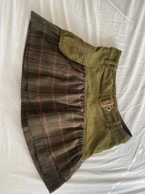 Grön rutig kortkjol med bälte - Lågmidjad kortkjol i militärgrönt med rutigt mönster i grönt, rött och vitt lite y2k stil ✨ köpte utan att prova och det visade sig att den inte passade 😭bild 1 är framsidan av kjolen, bild 2 är på sidan med en ficka och bild 3 är baksidan 🪩