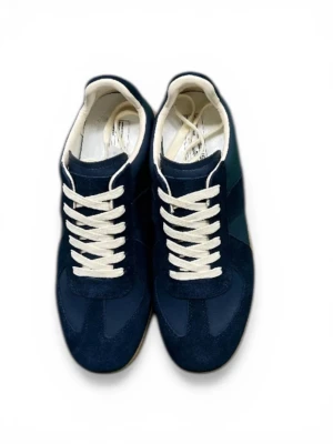 Margellas  - Snygga marinblå sneakers med ovandel i mocka och textil, vita snören och kontrasterande gummisula. Skorna har en klassisk låg siluett och vita detaljer vid hälen. Perfekta för dig som gillar stilrena och tidlösa sneakers.