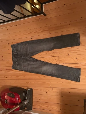 Mörkgrå slim fit jeans - Säljer ett par mörkgrå slim fit jeans med klassisk femficksdesign och snygga slitningar. Jeansen har smal passform och raka ben, perfekta till en avslappnad stil. Materialet är troligtvis bomullsdenim med lite stretch för extra komfort. passar även L31