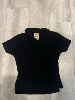 Svart frotté piké från OAS - Säljer en svart frotté piké från OAS med korta ärmar och klassisk krage. Toppen har en bröstficka och är gjord i mjuk frotté som ger en skön känsla. Perfekt för dig som gillar stilrena och bekväma plagg.