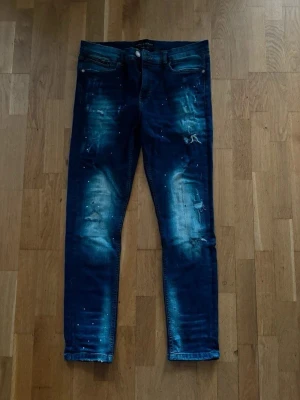 Blå distressed jeans Supply & Demand - Snygga blå jeans från Supply & Demand med slitningar och blekta detaljer. Modellen har smal passform och coola slitna partier framtill. Perfekta för dig som gillar en streetinspirerad look.