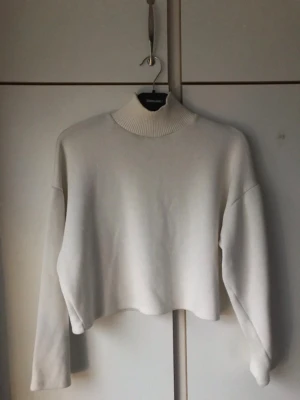 Vit croppad tröja med polokrage - Säljer en stilren vit croppad tröja från Zara med hög polokrage och långa ärmar. Tröjan har en enkel och clean design som passar perfekt till jeans eller kjol. Materialet känns mjukt och bekvämt mot huden.
