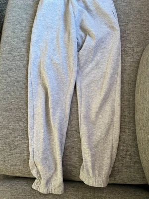 Grå mjukisbyxor med resår - Säljer ett par klassiska grå mjukisbyxor med resår i bensluten och avslappnad passform. Perfekta för chill dagar hemma eller när du vill ha det extra bekvämt. Tillverkade i mjukt sweatshirtmaterial som känns skönt mot huden.