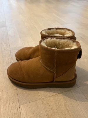 Bruna UGG boots - Klassiska bruna original UGG boots i mocka med mjukt fårskinnsfoder. Nästan som nys. Modellen är ankelhög och har en rund tå samt grov sula för extra komfort. 