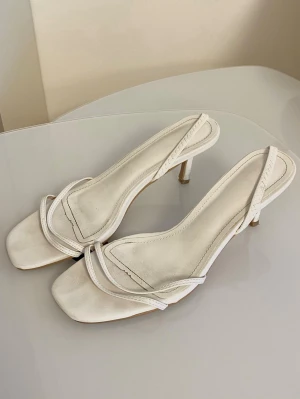 Vita klackskor - Stilrena vita klackar / sandaletter med smala remmar och  klack. De har fyrkantig tå och öppen häl.