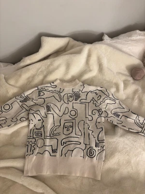 Beige stickad tröja med grafiskt mönster - Säljer en beige stickad tröja med svart grafiskt mönster ifrån monki. Använd en gång! Sjukt cool tröja!🩷🤍