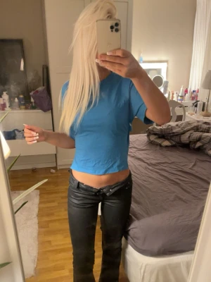 Blå croppad t-shirt med knytband - Trendig blå croppad t-shirt med rund hals och korta ärmar. Toppen har knytband i sidan som ger en snygg detalj och gör att du kan justera passformen. Tillverkad i mjukt bomullsliknande material, perfekt för en avslappnad och cool stil.