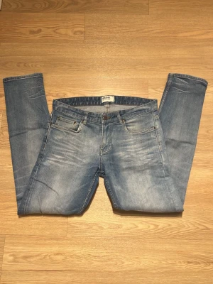 Dobber jeans - Säljer ett par ljusblå slim/regular fit jeans från dobber med klassisk femficksmodell och snygga slitningar framtill. Jeansen har normal midja och raka ben, tillverkade i bomull med lite stretch för extra komfort.