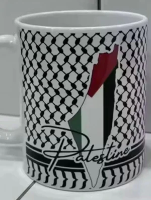 Mugg med Palestina-motiv( ny original förpackning  - Vit keramikmugg med svart mönster inspirerat av keffiyeh och en karta i färgerna rött, grönt, vitt och svart. Texten 'Palestine' står tryckt på framsidan. Perfekt för te eller kaffe och levereras i skyddande förpackning.