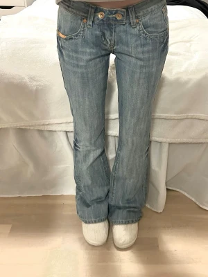 Low waist jeans bootcut - Säljer ett par ljusblå bootcut jeans med snygga broderade detaljer på bakfickorna och slitningar framtill. Jeansen har låg midja. De är köpta för 1200kr och aldrig använda då de var lite stora där bak. Prislappen är avdragen då jag trodde jag skulle använda de. Storlek xs/27