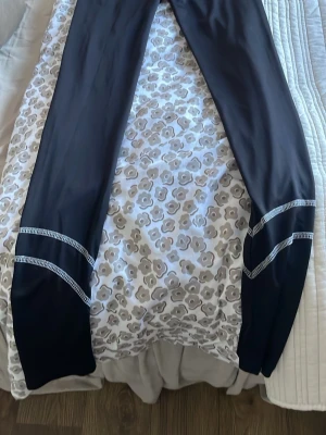 Svarta leggings från Projob - Säljer ett par svarta leggings från Projob med grå kontrastsömmar. De har elastisk midja och är tillverkade i ett stretchigt material som passar perfekt för träning eller chill. Snygga detaljer med sömmar över benen för en sportig look. Underställ