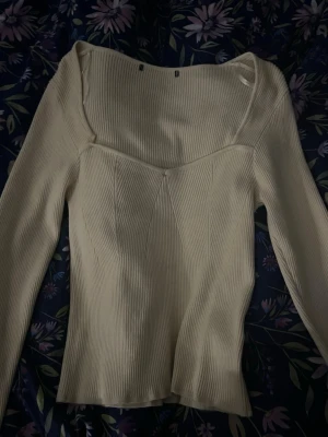 Ljusbeige ribbad långärmad topp - Trendig ljusbeige topp med ribbad struktur och lång ärm. Toppen har en snygg v-ringad skärning och sitter figurnära. Perfekt att styla med jeans eller kjol för en clean look. Tröjan är storlek 38 och byxorna var storlek 44 men har krympt till storlek 40/42