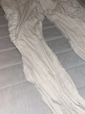 Vita linnebyxor med resår - Säljer ett par vita linnebyxor med avslappnad passform och resår i midjan samt längs benen. Byxorna har en ledig och luftig stil, perfekta för varma dagar. Materialet är tunt och mjukt linne som ger en skön känsla.