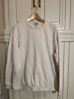 Vit basic sweatshirt - En enkel vit sweatshirt med rund hals och långa ärmar. Tröjan har en avslappnad passform. Perfekt att matcha med jeans eller mjukisbyxor. Små fläckar på magen som inte går bort